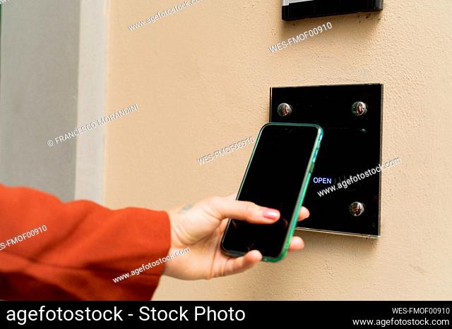 Close-up of woman opening door with smartphone