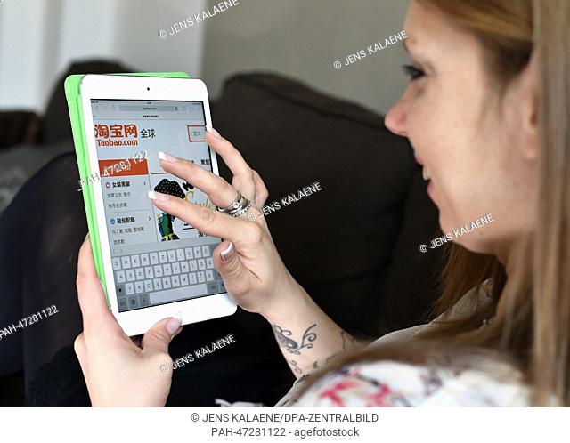 ILLUSTRATION - A young woman browses on her tablet computer through the web page of Chinese online auction platform Taobao in Berlin, Germany, 19 March 2014