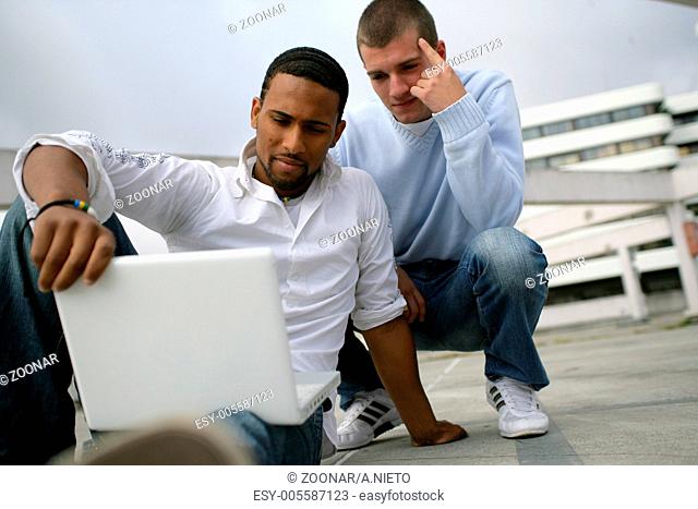 Two men outdoors with computer