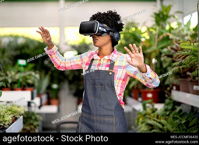 Gardener wearing virtual reality headset gesturing at plant nursery