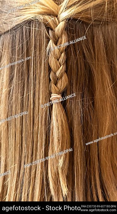 SYMBOL - 28 July 2023, Baden-Württemberg, Mannheim: A young woman wears braided hair at her graduation ceremony in the university