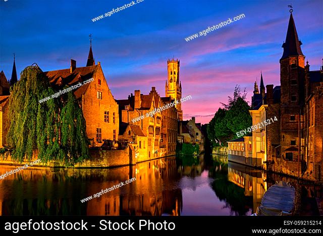 Famous view of Bruges tourist landmark attraction - Rozenhoedkaai canal with Belfry and old houses along canal with tree in the night. Brugge, Belgium