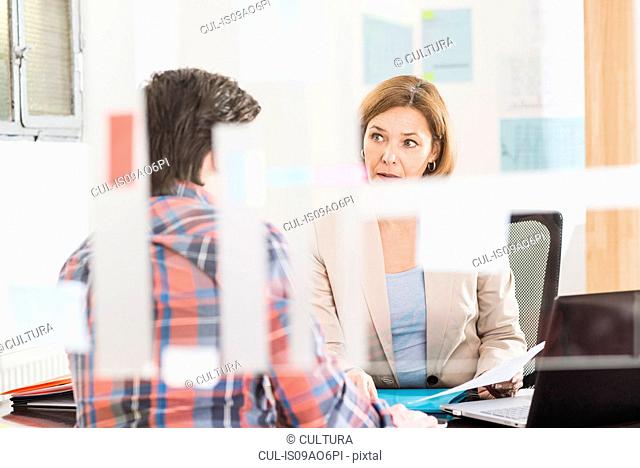 Businesswoman talking to businessman at office desk