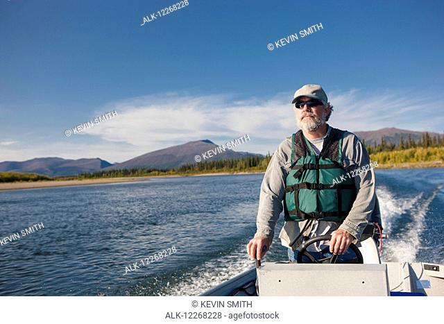 Man driving a motor boat down the Kobuk River, Shungnak, Arctic Alaska, summer