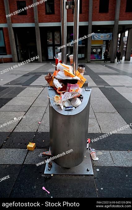 11 March 2023, North Rhine-Westphalia, Cologne: A full public trash can, trash cans overflowing with disposable packaging, coffee cups, etc