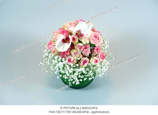 14 March 2018,  Germany, Berlin: A colourful bouquet of flowers with pink roses, white moth orchids, white gypsophila in a green vase