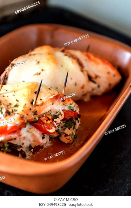 Baked poultry fillet stuffed with soft cheese, tomatoes and herbs in a ceramic baking dish. The concept of the proper beneficial health food, diet