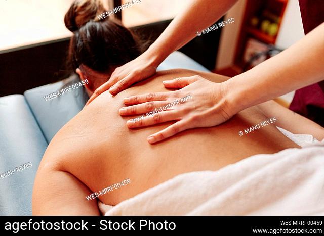 Woman having back massage while lying on stretcher