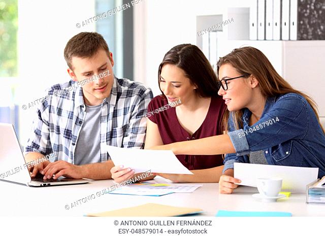 Three entrepreneurs analyzing and commenting reports together sitting in a desk at office