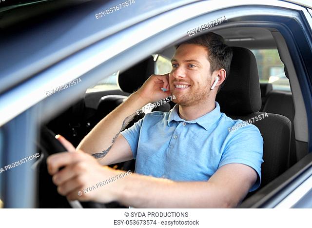 man or driver with wireless earphones driving car