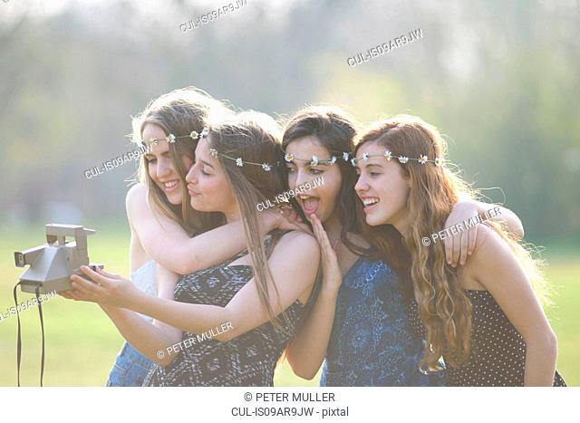 Four teenage girls in park taking instant camera selfie