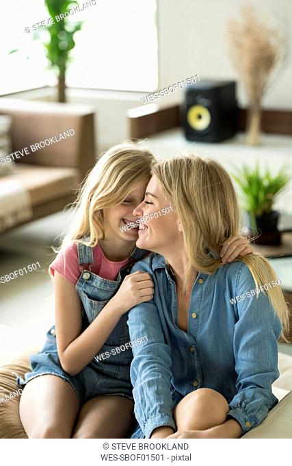 Happy mother and daughter cuddling and relaxing on a couch in a modern living room