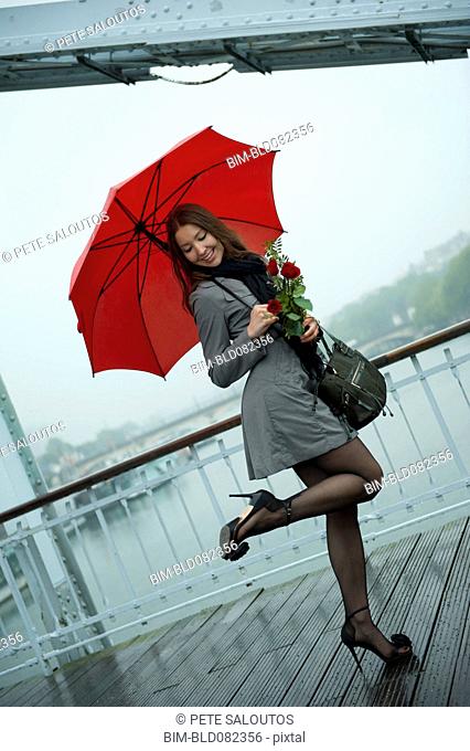 Caucasian woman in high heel shoes with red umbrella
