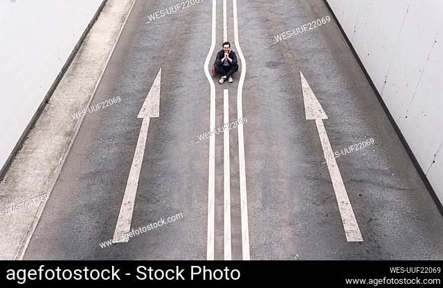 Young man sitting on road marking