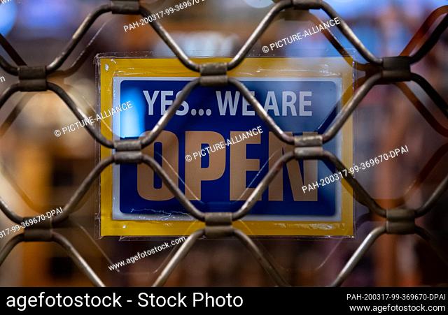 17 March 2020, Bavaria, Munich: A sign saying ""Yes...we are Open"" can be seen at a closed shop shortly after closing time