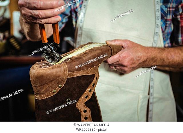 Mid section of shoemaker repairing a shoe
