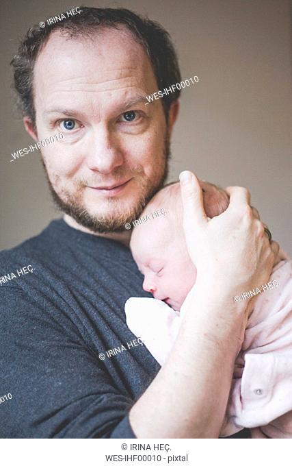 Portrait of father holding his sleeping newborn baby daughter