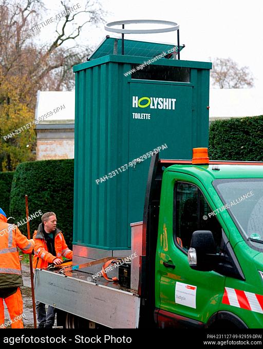 27 November 2023, North Rhine-Westphalia, Cologne: The ""Holy Shit"" dry toilet is brought to its place in the Volksgarten by employees of the City of Cologne