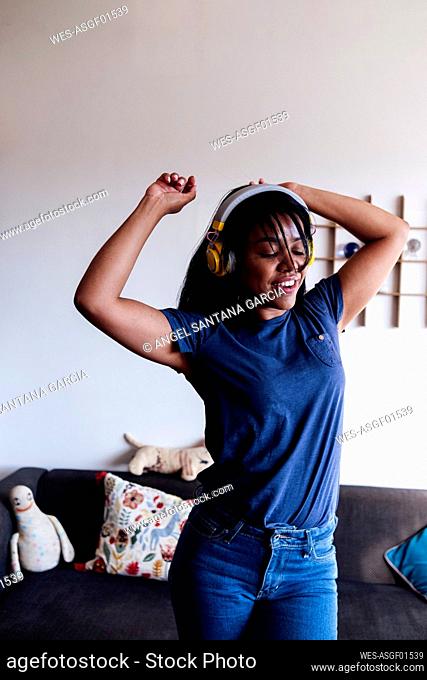 Woman with arms raised dancing in living room