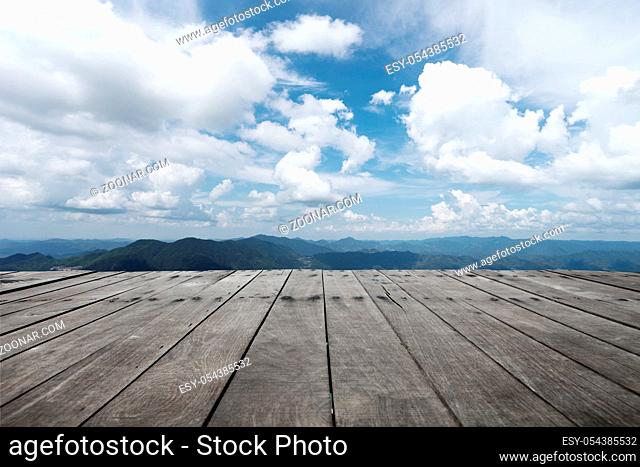 empty wooden floor and green hill in blue cloud sky