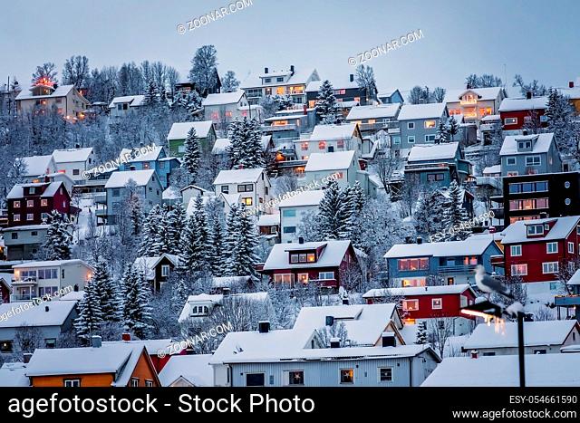 Residential hillside houses in Tromso suburb covered in a deep snow in winter, northern Norway