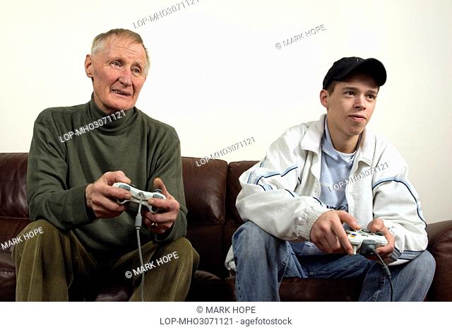 England, County Durham, Durham. A grandfather and his grandson sitting on a sofa playing a computer game