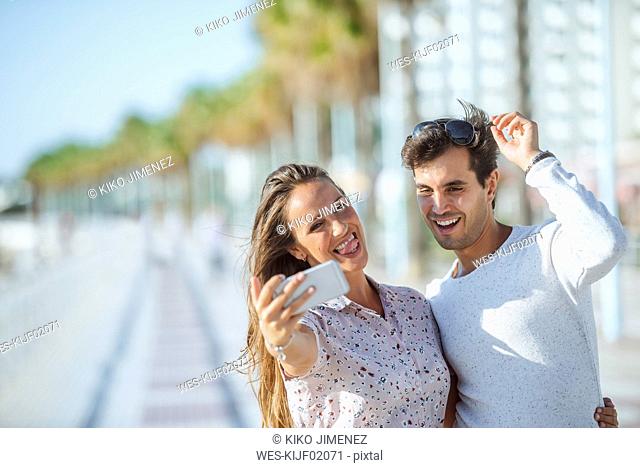 Happy young couple taking a selfie on promenade