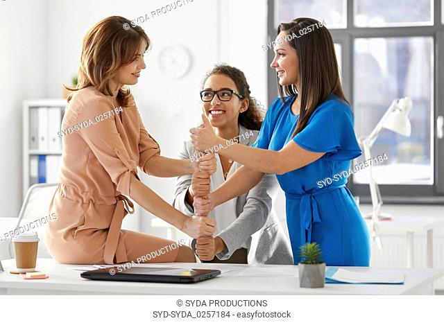 group of businesswomen showing thumbs up at office