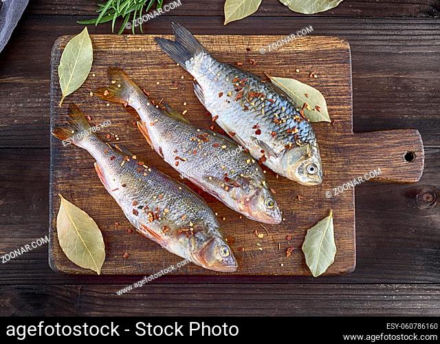 river fish crucian and perch in spices and salt on a brown wooden cutting board