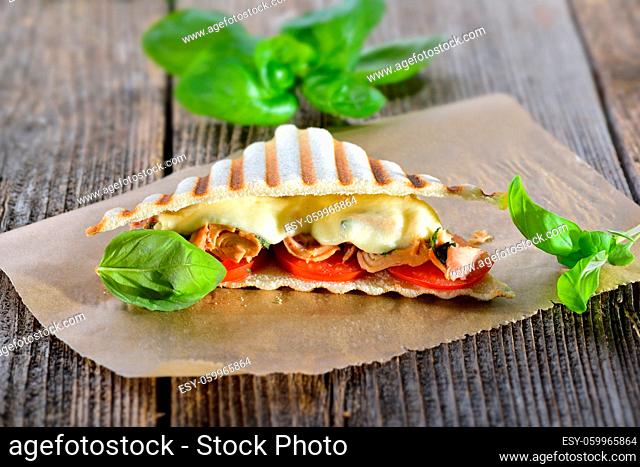 Getoastetes italienisches Panini mit Thunfisch, Tomaten, geschmolzenem Mozzarella und frischem Basilikum - Toasted panini with tuna fish, tomatoes