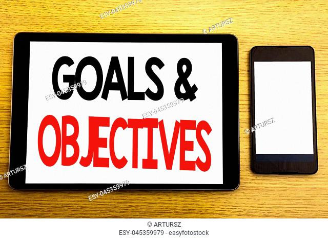 Writing text showing Goals Objectives. Business concept for Plan Success Vision Written on tablet, wooden background with sticky note and pen