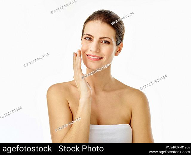 Portrait of smiling woman applying moisturizer on her face