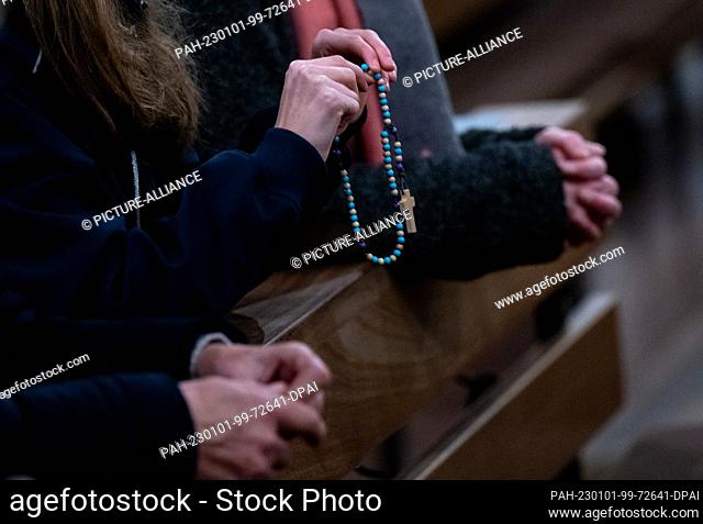 01 January 2023, Bavaria, Marktl: A woman holds a rosary in her hands at St. Oswald Church during a service for Pope Emeritus Benedict XVI
