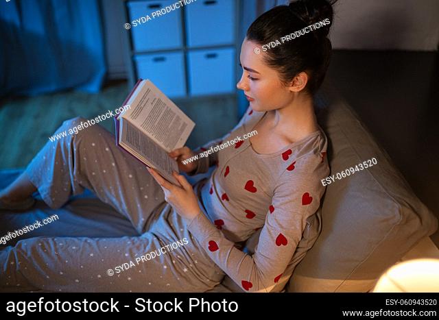 teenage girl reading book in bed at home