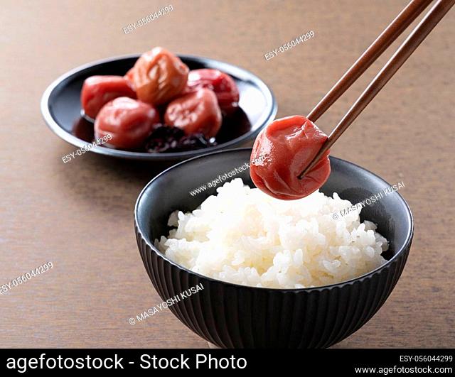 Japanese pickled plum and freshly cooked rice with a piece of pickled plum with chopsticks