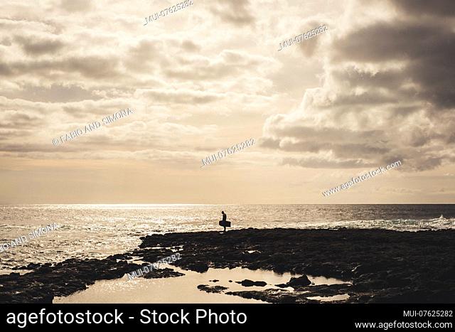 lonely surfer with his thoughts looking at the ocean. Stand up isolated man challenge his fears