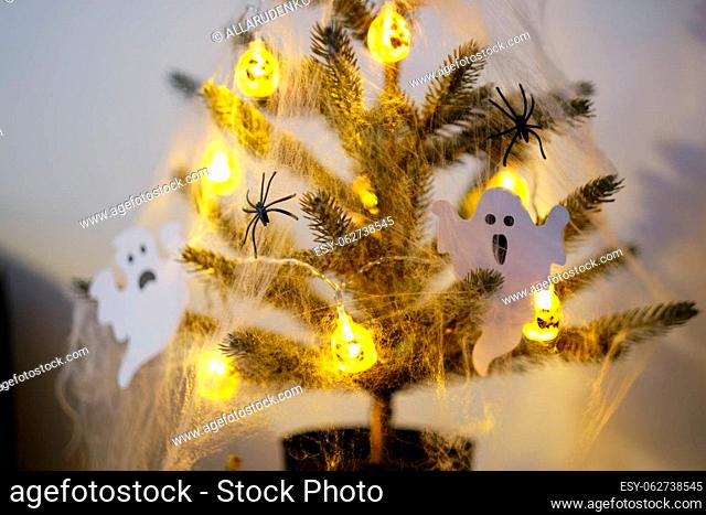 Close-up of a halloween tree decorated with lights, cobwebs and decorative ghosts. Halloween home decorations. Selective focus
