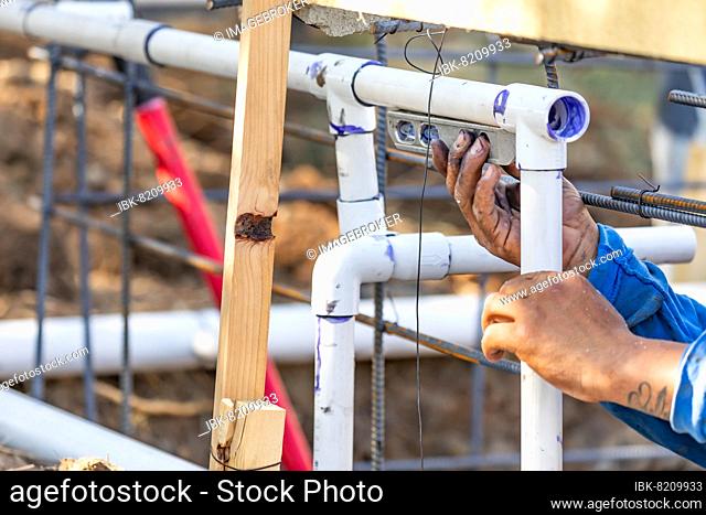 Plumber using level while installing PVC pipe at construction site