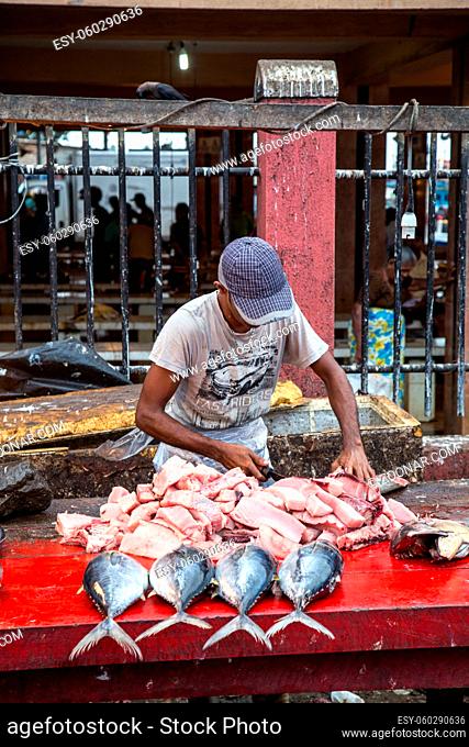 Negombo, Sri Lanka - July 25, 2018: A man cutting sih into pieces at the early morning fish market