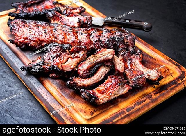 Barbecue pork spare loin ribs St Louis cut with hot honey chili marinade sliced and burnt as closeup on a wooden cutting board