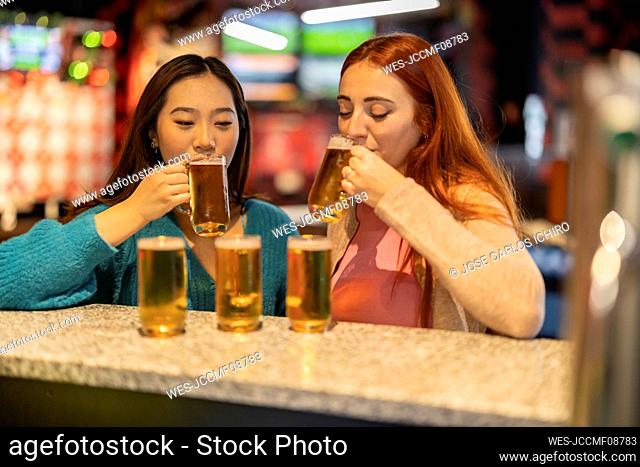 Multiracial women drinking beer at bowling alley