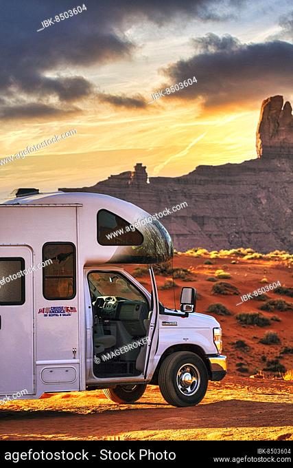 Motorhome with company logo parked on gravel road in front of striking rock formation, rock needle, panoramic road in Monument Valley, sunset, Arizona, USA