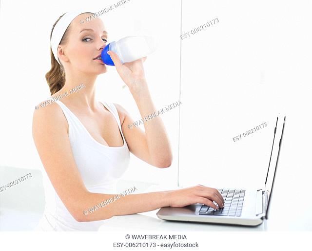 Serious pretty sportswoman drinking water