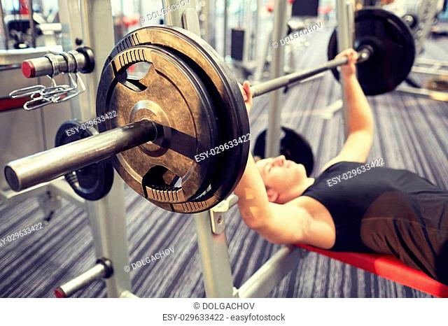 sport, bodybuilding, lifestyle and people concept - close up of man flexing biceps with barbell in gym