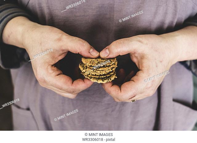 Close up of person holding small stack of freshly baked seeded crackers