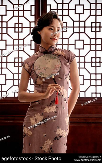 Oriental women wear qipao with a fan