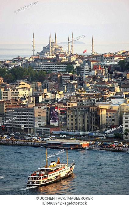 View across the Eminoenue district towards mosques with a ferryboat crossing the Golden Horn, Istanbul, Turkey