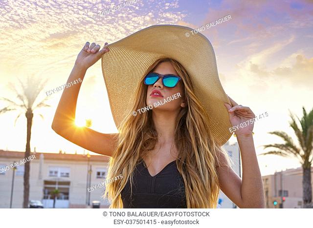 Blond teen girl sunglasses and pamela sun hat at palm tree sunset