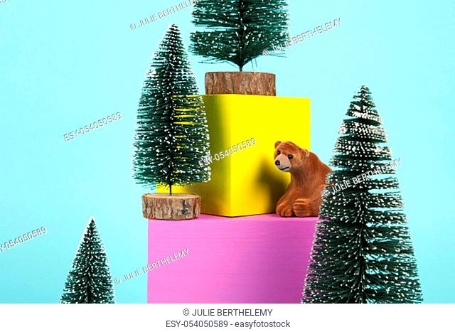 brown bear in the middle of Snowy Christmas trees on a pile of coloured cubes. Play of vibrant colors. Minimal still life color photography