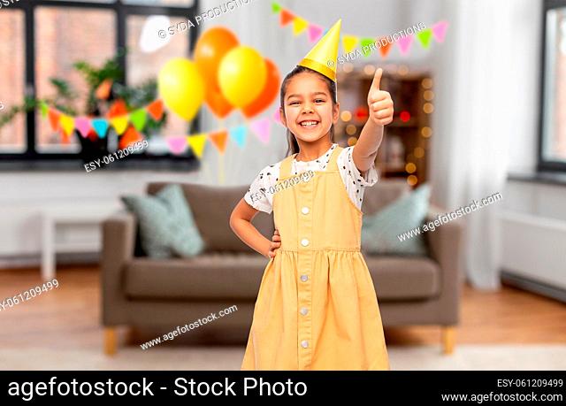 girl showing thumbs up at birthday party at home